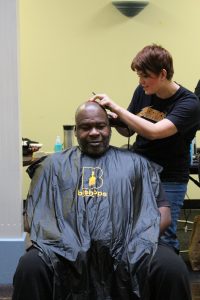 Человек получает стрижку от стихотворцев Bishops Barbershop на бесплатном стрижке Impact NW